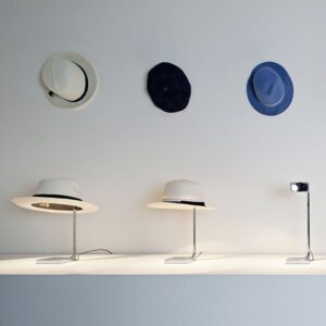 Tre lampade chapo cromo di flos in esposizione con tre cappelli in parete